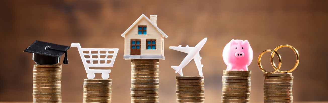 stacked coins with grad cap, cart, house, airplane, piggy bank and rings stacked on them